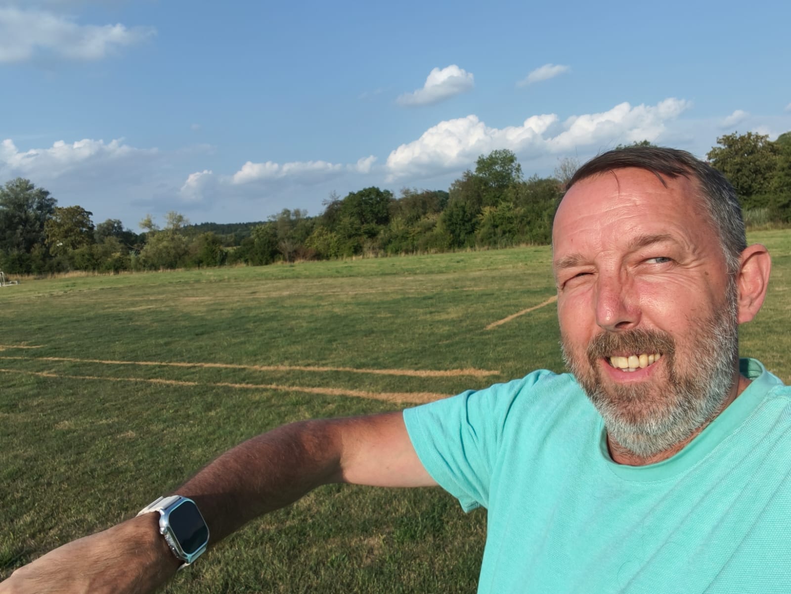 Torsten Merkel lächelt im Freien, die PSAIM-Uhr sichtbar am Handgelenk
